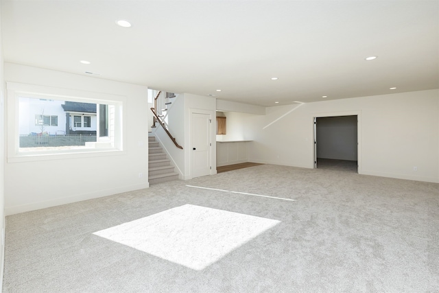 basement featuring light carpet, stairs, and recessed lighting