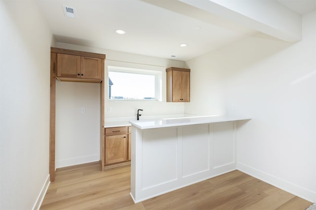 kitchen with light countertops, light wood-type flooring, visible vents, and baseboards