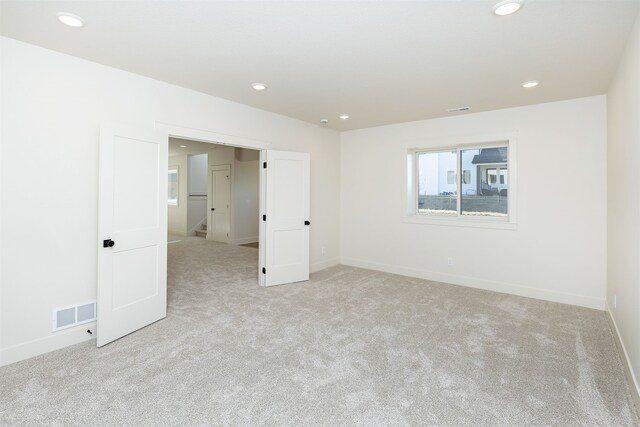 unfurnished room with recessed lighting, visible vents, and light carpet