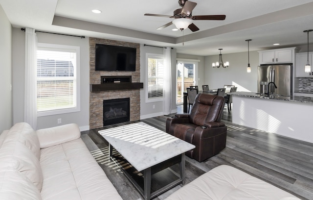 living room featuring a fireplace, ceiling fan with notable chandelier, and dark hardwood / wood-style floors