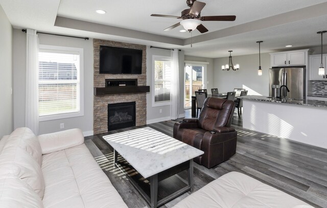 812 SE 15th St, Grimes, IA 50111 - living area featuring a fireplace, a ceiling fan, dark wood-style flooring, a tray ceiling, and plenty of natural light