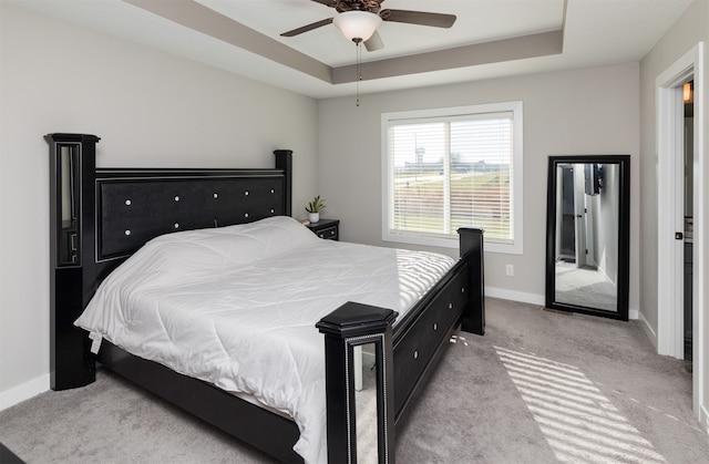 bedroom featuring ceiling fan, light colored carpet, and a tray ceiling