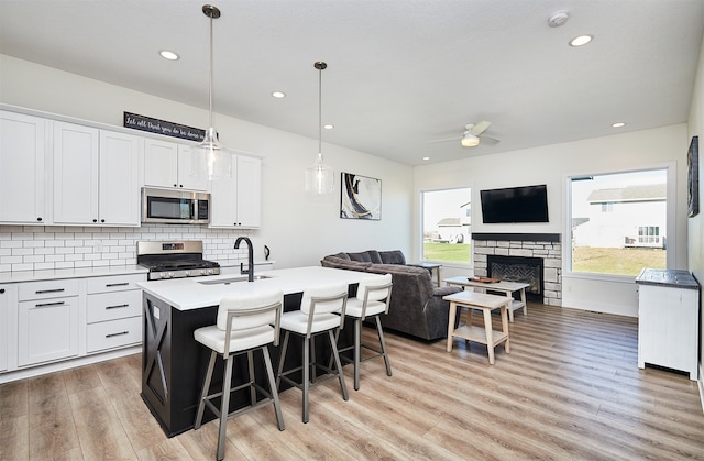 kitchen featuring appliances with stainless steel finishes, sink, white cabinetry, and an island with sink