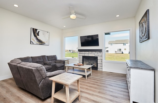 living room with ceiling fan, light wood-type flooring, and a fireplace