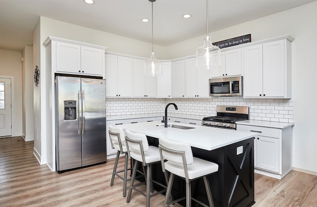 kitchen featuring white cabinets, appliances with stainless steel finishes, hanging light fixtures, and sink