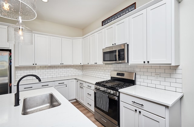 kitchen with white cabinets, decorative light fixtures, decorative backsplash, and stainless steel appliances