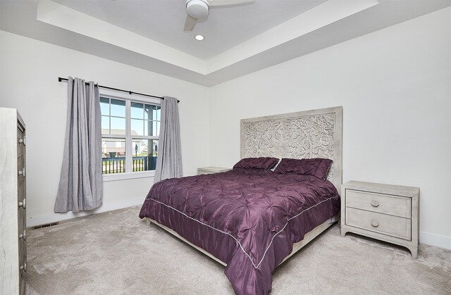 carpeted bedroom featuring a raised ceiling and ceiling fan