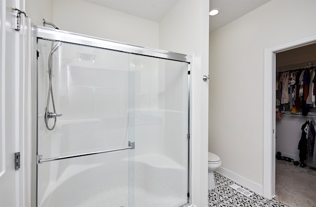 bathroom with tile patterned floors, toilet, and a shower with shower door