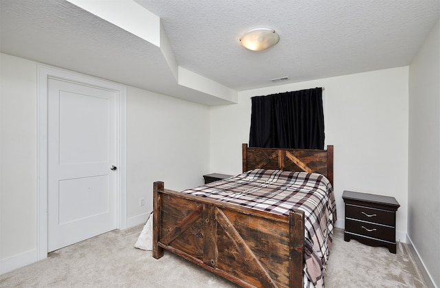 bedroom with light colored carpet and a textured ceiling