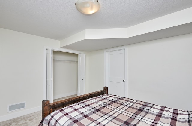 carpeted bedroom with a closet and a textured ceiling