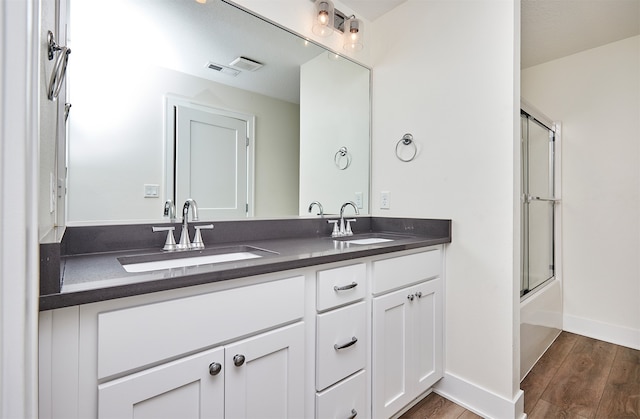 bathroom featuring hardwood / wood-style floors, vanity, and combined bath / shower with glass door