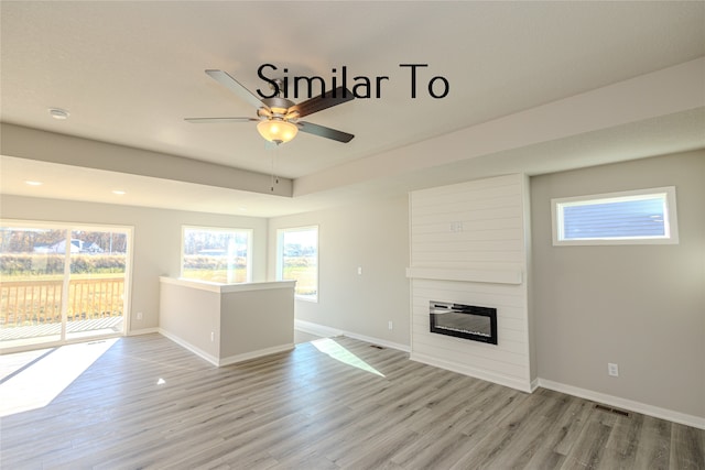 unfurnished living room with a fireplace, ceiling fan, and light wood-type flooring