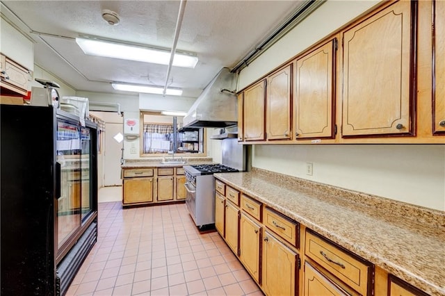 kitchen featuring black fridge, stainless steel range with gas cooktop, light tile patterned floors, a textured ceiling, and island range hood