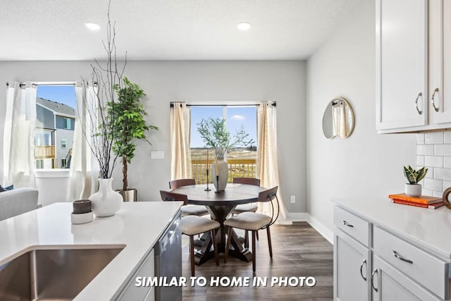 dining space with dark wood finished floors, plenty of natural light, baseboards, and a textured ceiling