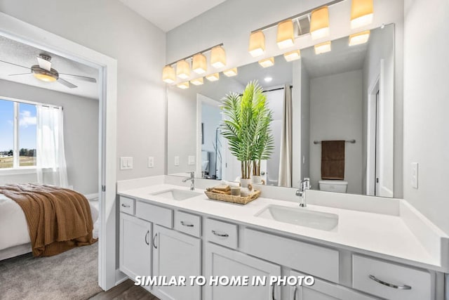 bathroom featuring ceiling fan, ensuite bath, double vanity, and a sink