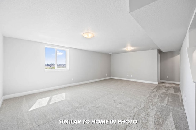 below grade area featuring baseboards, carpet, and a textured ceiling