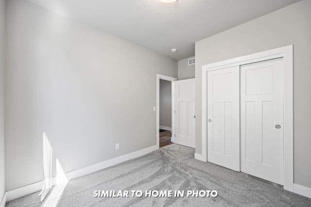 unfurnished bedroom with baseboards, visible vents, carpet floors, and a closet