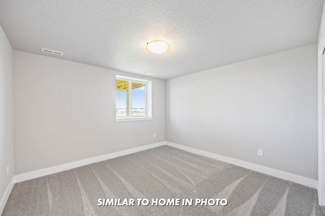 carpeted empty room with visible vents, baseboards, and a textured ceiling