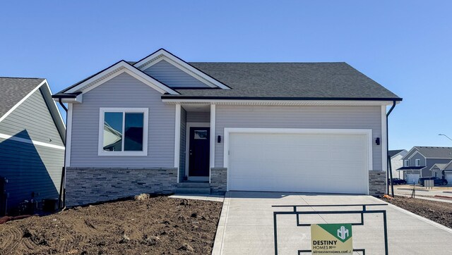 view of front of property featuring a garage, stone siding, driveway, and roof with shingles