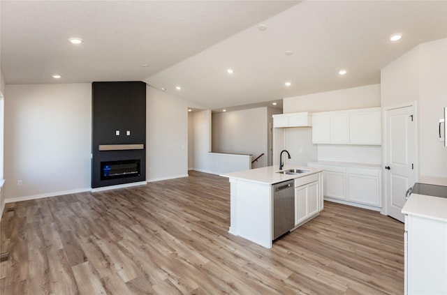 kitchen featuring white cabinetry, lofted ceiling, a kitchen island with sink, a sink, and dishwasher