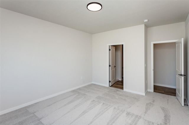 unfurnished bedroom featuring baseboards and light carpet