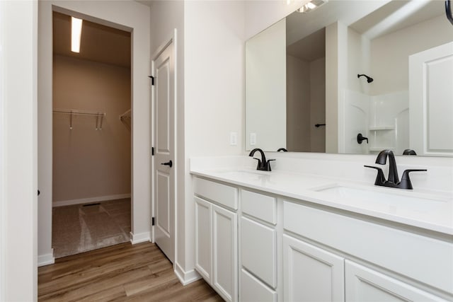 full bath featuring wood finished floors, a spacious closet, a shower, and a sink