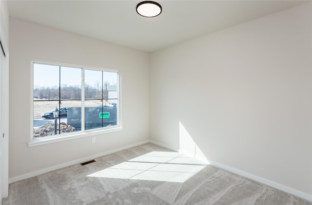 carpeted spare room with visible vents and baseboards