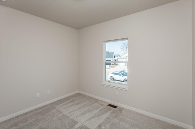 unfurnished room featuring visible vents, baseboards, and light colored carpet