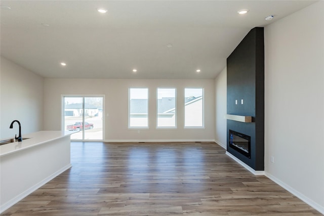 unfurnished living room featuring recessed lighting, wood finished floors, and a fireplace