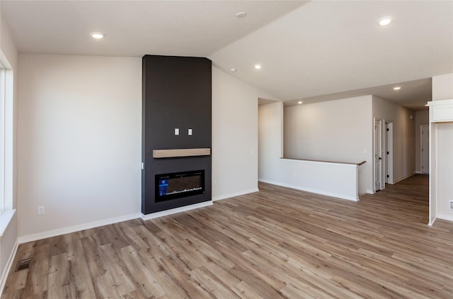 unfurnished living room with recessed lighting, a large fireplace, light wood-style floors, and lofted ceiling