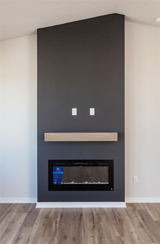 interior details with wood finished floors, a fireplace, and baseboards