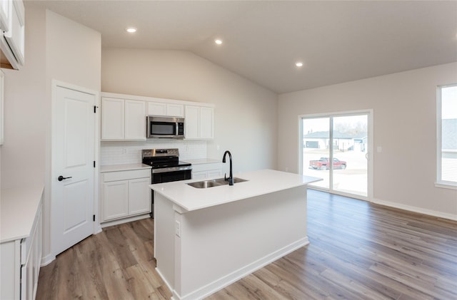 kitchen with backsplash, lofted ceiling, appliances with stainless steel finishes, light wood-style floors, and a sink