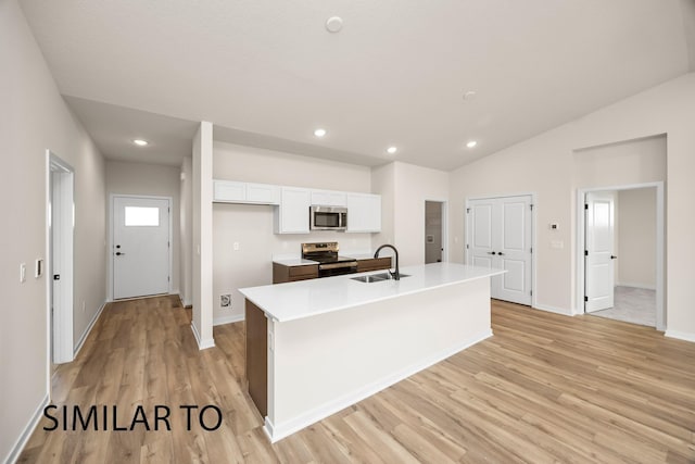 kitchen featuring a center island with sink, stainless steel appliances, light wood-style floors, white cabinetry, and a sink