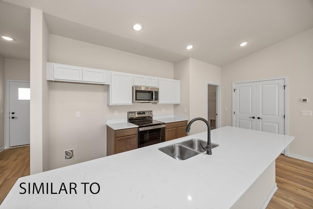 kitchen featuring light wood-style flooring, a sink, stainless steel appliances, light countertops, and white cabinetry