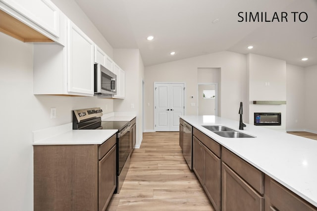 kitchen with light countertops, light wood-type flooring, appliances with stainless steel finishes, white cabinets, and a sink