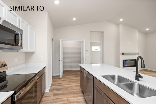 kitchen with a sink, light wood finished floors, white cabinetry, and stainless steel appliances