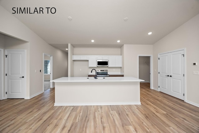 kitchen with light wood finished floors, a sink, appliances with stainless steel finishes, white cabinets, and light countertops