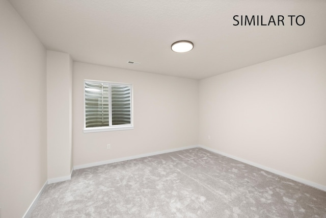 carpeted spare room featuring baseboards and visible vents