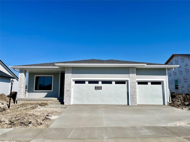 prairie-style home featuring driveway, an attached garage, and a shingled roof