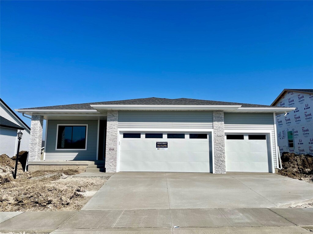 1048 NE 64th Ave, Des Moines, IA 50313 - prairie-style house featuring stone siding, a garage, and concrete driveway