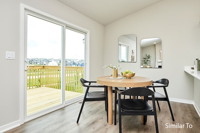 dining space with wood-type flooring and vaulted ceiling