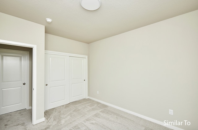 unfurnished bedroom with light colored carpet and a closet