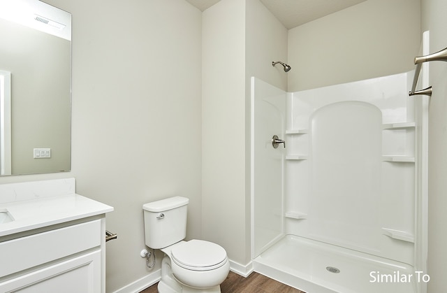 bathroom with toilet, vanity, hardwood / wood-style floors, and walk in shower