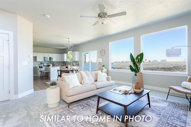 living room featuring ceiling fan, baseboards, and a textured ceiling