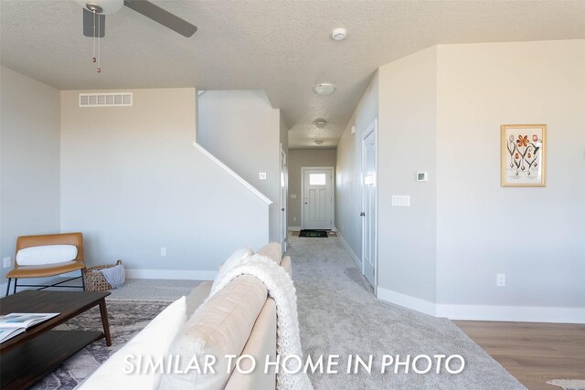 living area featuring visible vents, ceiling fan, a textured ceiling, and baseboards