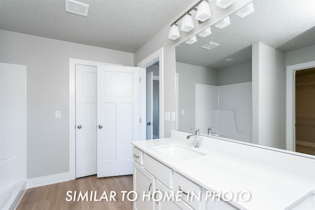 bathroom featuring visible vents, wood finished floors, vanity, baseboards, and a spacious closet