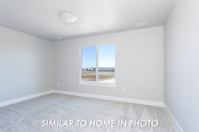 carpeted spare room with baseboards, visible vents, and a textured ceiling