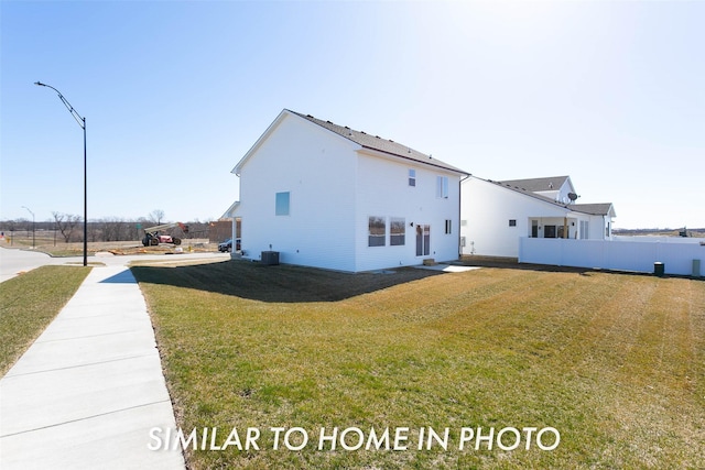 view of side of property featuring central AC, a yard, and fence