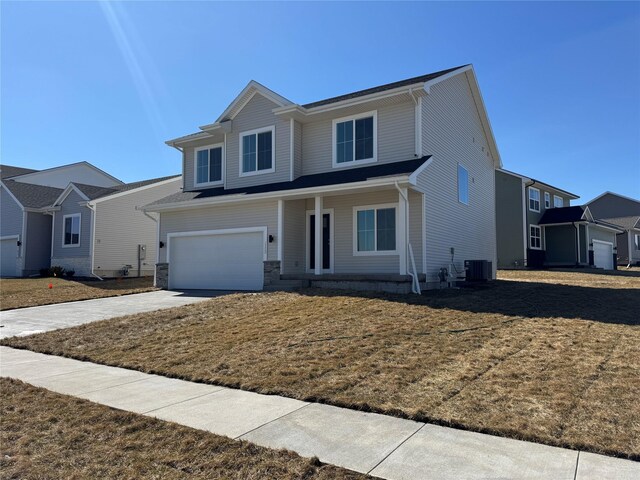 view of front of property featuring concrete driveway, an attached garage, a front yard, and central AC