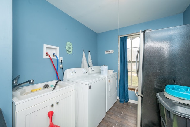 clothes washing area featuring separate washer and dryer, dark hardwood / wood-style floors, cabinets, and sink